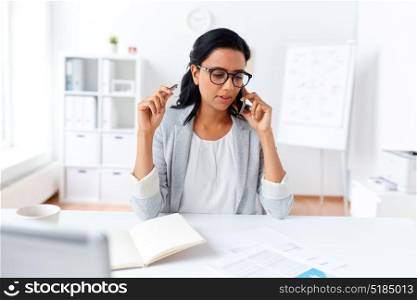 business, technology, communication and people concept - businesswoman or secretary calling on smartphone and writing to notebook at office. businesswoman calling on smartphone at office