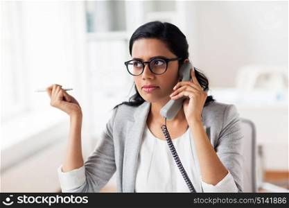 business, technology, communication and people concept - businesswoman or secretary calling on phone at office. businesswoman calling on phone at office