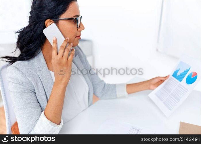 business, technology, communication and people concept - businesswoman with papers calling on smartphone at office. businesswoman calling on smartphone at office