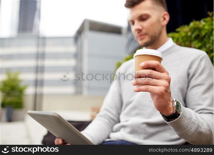business, technology, communication and people concept - close up of man with tablet pc computer drinking coffee from paper cup and sitting on city street