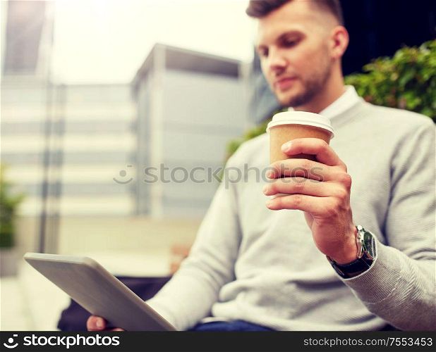 business, technology, communication and people concept - close up of man with tablet pc computer drinking coffee from paper cup and sitting on city street. man with tablet pc and coffee cup on city street