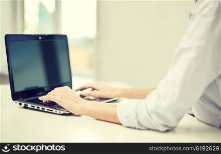 business, technology, communication and people concept - close up of woman typing on laptop computer at office or home