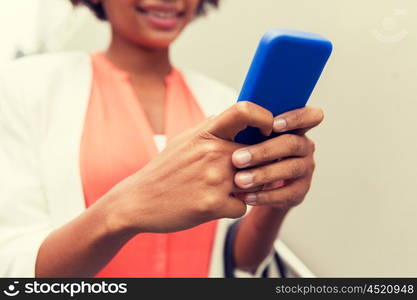 business, technology, communication and people concept - close up of young smiling african american businesswoman texting on smartphone in city