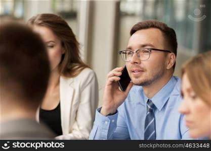 business, technology, communication and people concept - happy businessman calling on smartphone at office