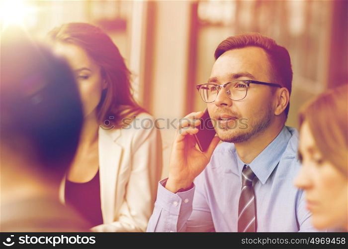 business, technology, communication and people concept - happy businessman calling on smartphone at office. businessman calling on smartphone at office