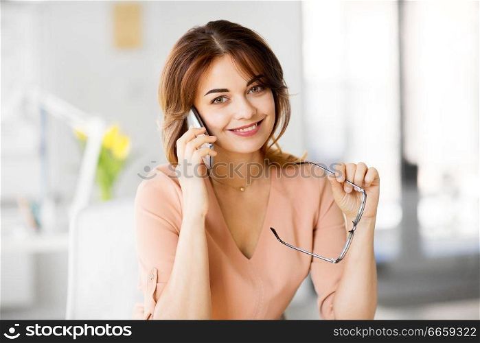 business, technology, communication and people concept - happy businesswoman calling on smartphone at office. businesswoman calling on smartphone at office