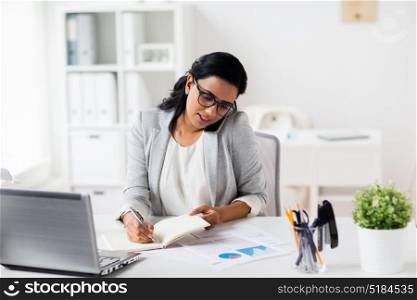business, technology, communication and people concept - happy businesswoman or secretary with notebook calling on smartphone at office. businesswoman calling on smartphone at office