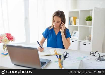 business, technology, communication and people concept - happy middle-aged woman calling on smartphone and writing to notebook at office or home. woman with notepad calling on smartphone at office