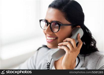 business, technology, communication and people concept - happy smiling businesswoman or secretary calling on phone at office. smiling businesswoman calling on phone at office