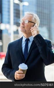 business, technology, communication and people concept - senior businessman with coffee cup calling on smartphone in city. senior businessman calling on smartphone in city