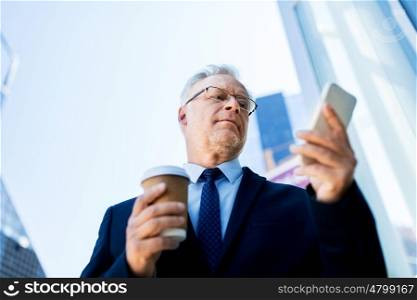 business, technology, communication and people concept - senior businessman with coffee cup and smartphone in city