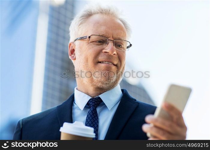 business, technology, communication and people concept - senior businessman with coffee cup and smartphone in city. businessman with smartphone and coffee in city