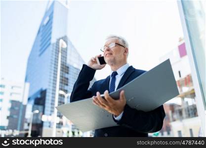 business, technology, communication and people concept - senior businessman with document folder calling on smartphone in city