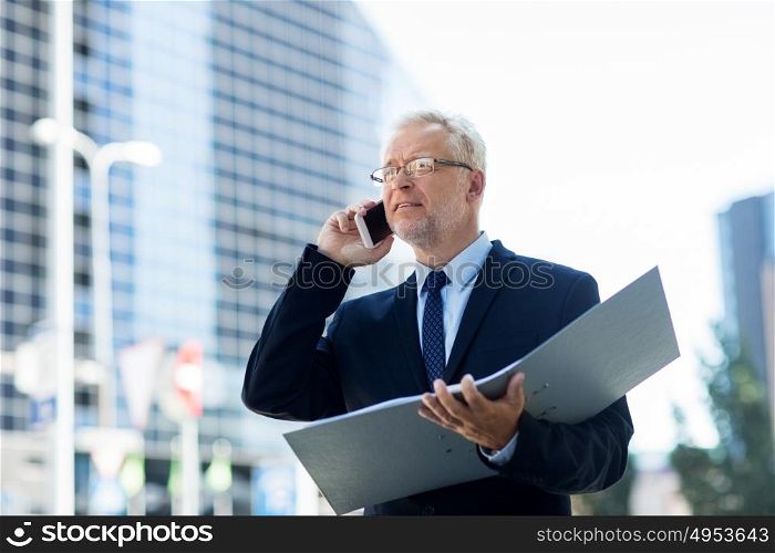 business, technology, communication and people concept - senior businessman with document folder calling on smartphone in city. senior businessman calling on smartphone in city