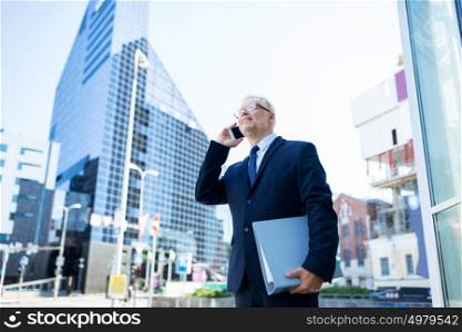 business, technology, communication and people concept - senior businessman with document folder calling on smartphone in city. senior businessman calling on smartphone in city