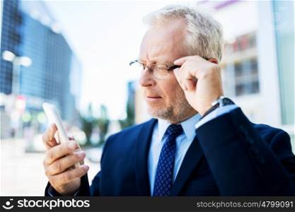 business, technology, communication and people concept - senior businessman with smartphone in city