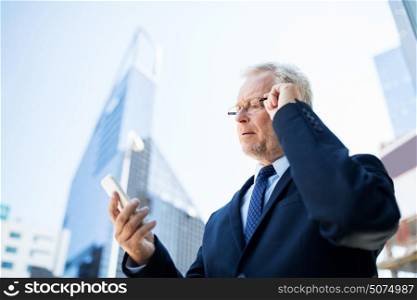business, technology, communication and people concept - senior businessman with smartphone in city. senior businessman with smartphone in city