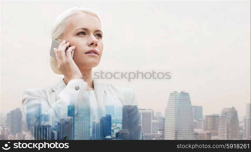 business, technology, communication and people concept - serious businesswoman with smartphone talking over city background