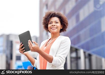 business, technology, communication and people concept - young smiling african american businesswoman with tablet pc computer in city
