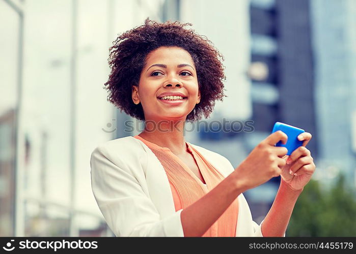 business, technology, communication and people concept - young smiling african american businesswoman with smartphone in city