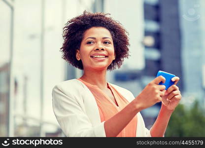 business, technology, communication and people concept - young smiling african american businesswoman with smartphone in city