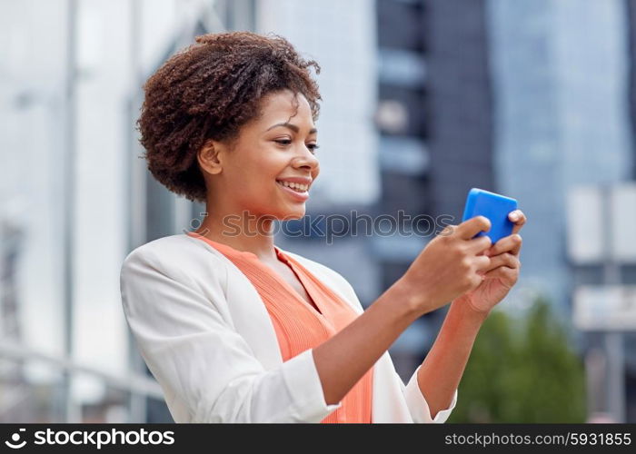 business, technology, communication and people concept - young smiling african american businesswoman with smartphone in city