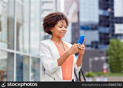 business, technology, communication and people concept - young smiling african american businesswoman with smartphone in city