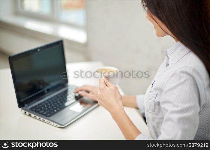 business, technology, communication, leisure and people concept - close up of woman with laptop computer typing and drinking coffee from cup at home or office
