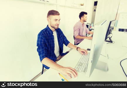 business, technology, education and people concept - happy young creative man or student with computer at office. creative man or student with computer at office