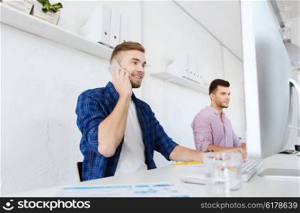 business, technology, education and people concept - happy young creative man or student with computer at office calling on smartphone