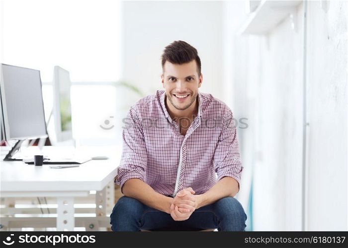business, technology, education and people concept - happy young creative man or student with computer at office