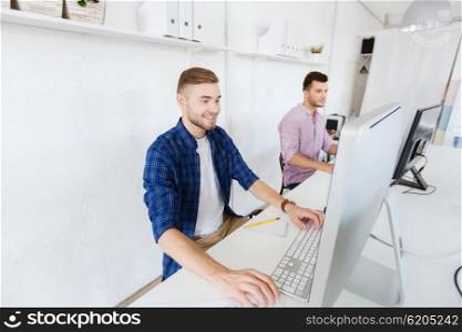 business, technology, education and people concept - happy young creative man or student with computer at office