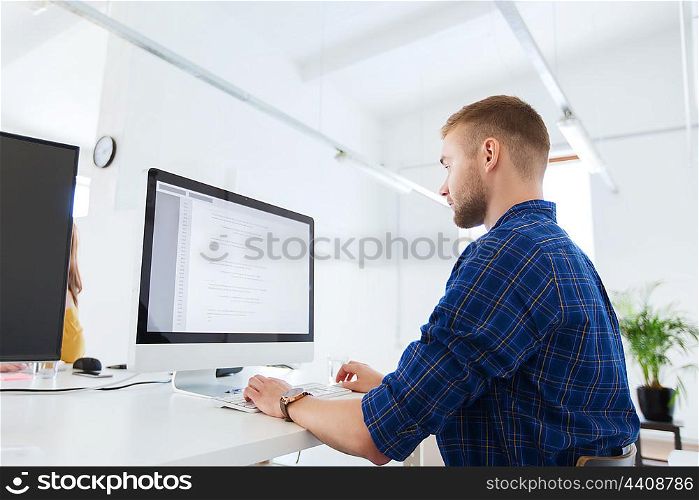 business, technology, education and people concept - young creative man or programmer with computer working at office