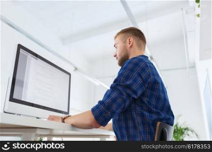 business, technology, education and people concept - young creative man or programmer with computer working at office