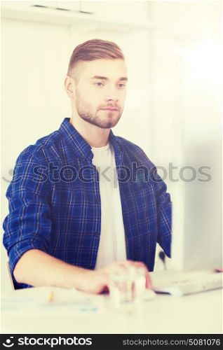 business, technology, education and people concept - young creative man or student with computer at office. creative man or student with computer at office