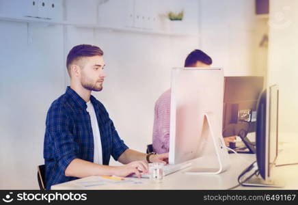 business, technology, education and people concept - young creative man or student with computer at office. creative man or student with computer at office. creative man or student with computer at office