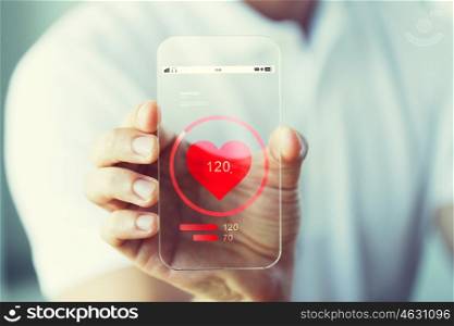 business, technology, health care and people concept - close up of male hand holding and showing transparent smartphone with heart rate icon
