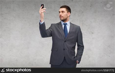 business, technology, internet and education concept - friendly young businessman with smartphone