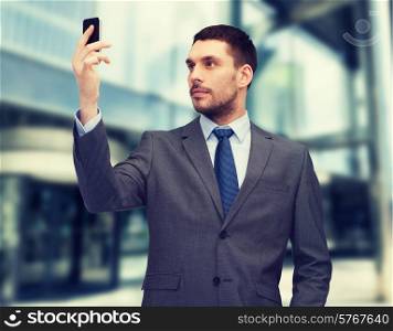 business, technology, internet and education concept - friendly young businessman with smartphone