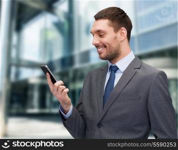 business, technology, internet and education concept - friendly young smiling businessman with smartphone