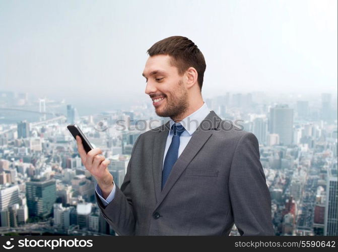 business, technology, internet and education concept - friendly young smiling businessman with smartphone