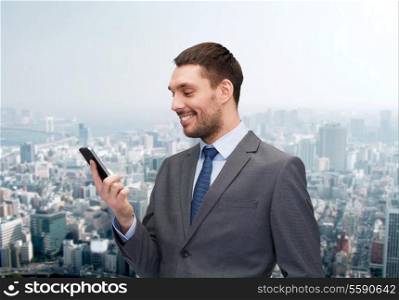 business, technology, internet and education concept - friendly young smiling businessman with smartphone