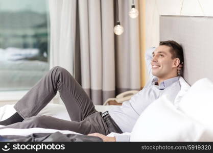 business, technology, internet and hotel concept - happy businesswoman lying in bed in hotel room