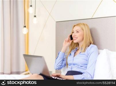 business, technology, internet and hotel concept - happy businesswoman with smartphone and laptop lying in hotel in bed
