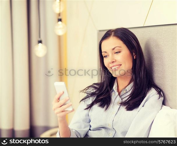 business, technology, internet and hotel concept - happy businesswoman with smartphone lying in hotel in bed