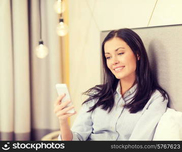 business, technology, internet and hotel concept - happy businesswoman with smartphone lying in hotel in bed