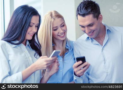 business, technology, internet and office concept - smiling business team with smartphones in office