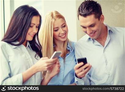 business, technology, internet and office concept - smiling business team with smartphones in office