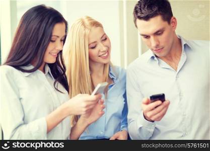 business, technology, internet and office concept - smiling business team with smartphones in office