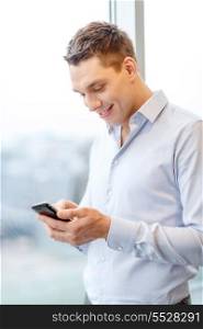 business, technology, internet and office concept - smiling businessman with smartphone in office